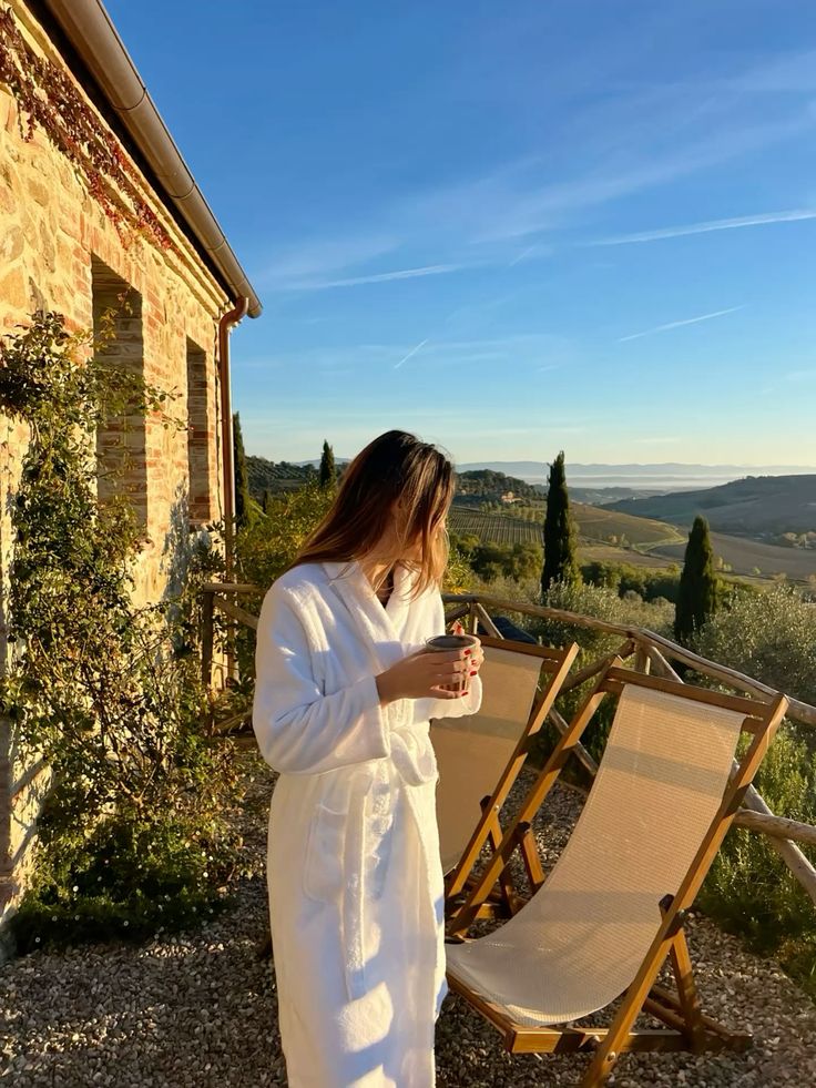 Woman in white robe overlooking Tuscan countryside