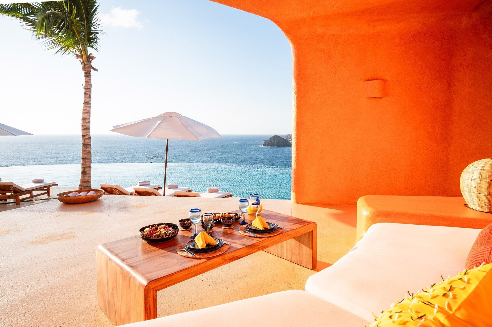 Coastal villa terrace with palm tree, ocean view, and dining table